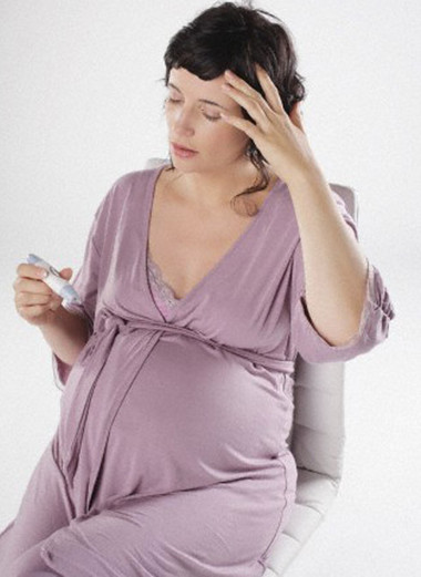 Pregnant woman holding thermometer